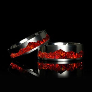 Könnte beinhalten: Zwei silberne Ringe mit einem roten Edelstein-Inlay. Die Ringe sind übereinander gestapelt.