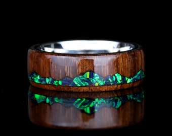May include: A wooden ring with a silver band and a green and blue opal inlay. The ring is polished and has a smooth finish.