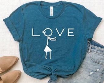 May include: A teal blue t-shirt with a white stick figure wearing a flower crown and a hula skirt. The text "LOVE" is printed above the figure.