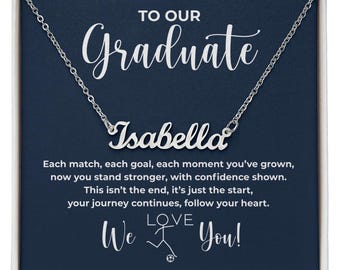 Könnte beinhalten: Eine silberne Halskette mit dem Namen "Isabella" in Schreibschrift, präsentiert auf einem marineblauen Hintergrund mit den Worten "TO OUR Graduate" darüber. Die Karte enthält eine Glückwunschbotschaft und die Worte "We Love You!"