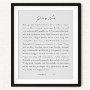 May include: A framed wall art print featuring the title Silvery Moon in elegant script, followed by lyrics and a prose passage, ending with the name Beatrice Sterling. The text is printed in black on a light gray background within a black frame.