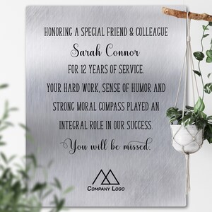 May include: A silver plaque with a brushed metal finish honoring Sarah Connor for 12 years of service. The plaque reads "Honoring a special friend & colleague Sarah Connor for 12 years of service. Your hard work, sense of humor and strong moral compass played an integral role in our success. You will be missed." The plaque also features a company logo with two triangles.
