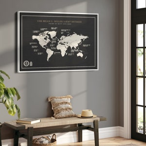 May include: A black and white world map print with a silver frame. The map shows the locations of various military bases around the world. The text at the top of the print reads "CSM Brian C. Miller (Army Retired) Tours of Duty 1995-2022".