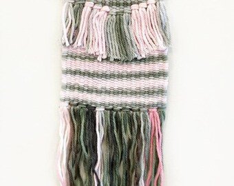 Hand woven wall hanging in pink and green