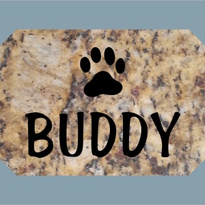 May include: A brown granite pet memorial with a black paw print and the name "BUDDY" in black lettering.