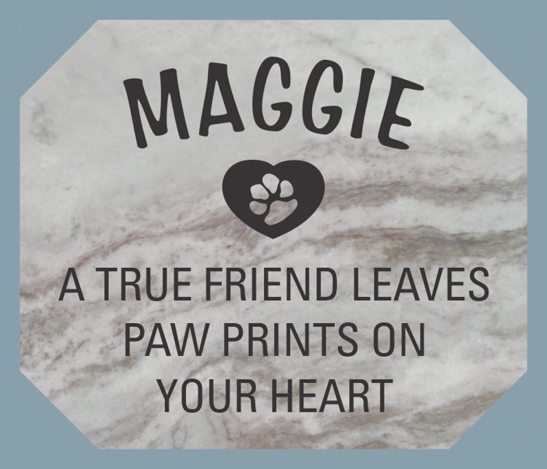 May include: A gray stone memorial with the name Maggie and the text "A true friend leaves paw prints on your heart". A black heart with a paw print is in the center of the stone.