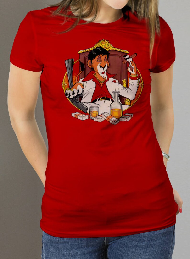 May include: A red t-shirt with a cartoon lion wearing a white suit and holding a cigar. The lion is sitting on a throne with money and a bottle of liquor in front of him.