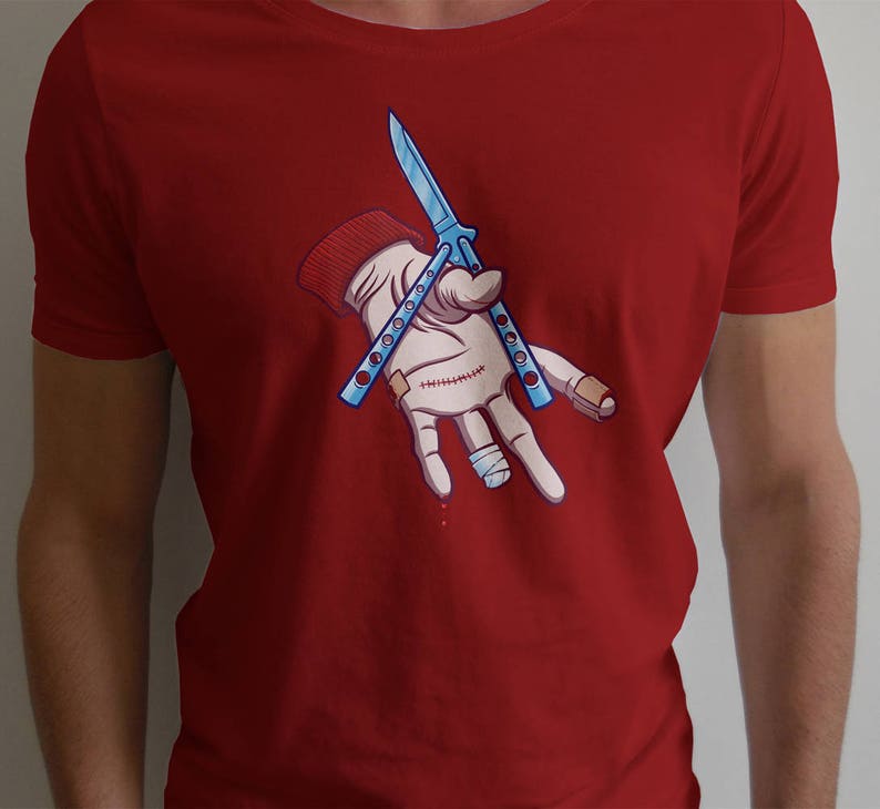 Puede incluir: Camiseta roja con un gr&aacute;fico de una mano sosteniendo un cuchillo mariposa azul. La mano est&aacute; vendada y tiene una gota de sangre.