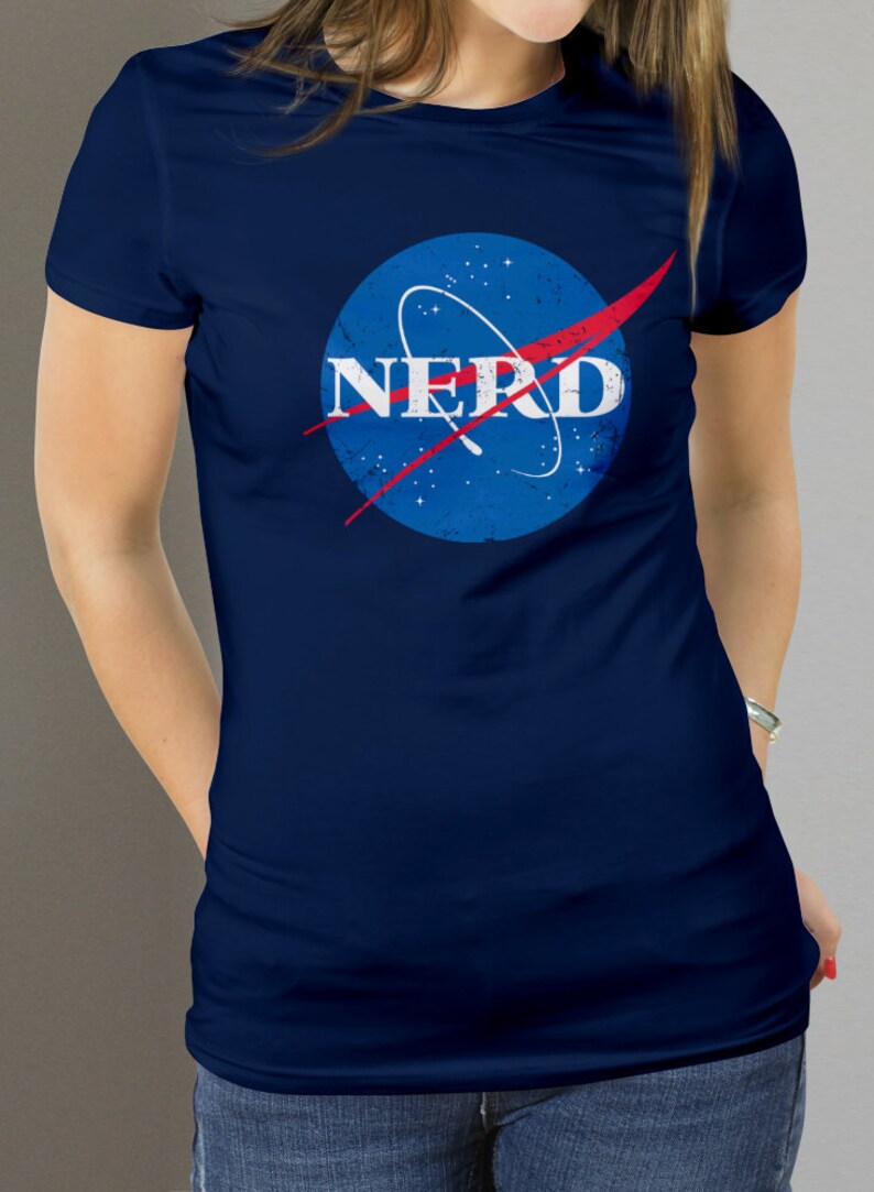 May include: A navy blue t-shirt with a distressed blue and red NASA logo that says "NERD" in white letters.