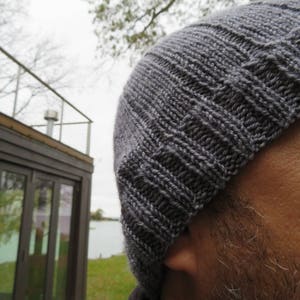 Puede incluir: Primer plano de un gorro de punto gris. El gorro est&aacute; hecho de un hilo suave y texturizado y tiene un dise&ntilde;o simple y cl&aacute;sico.