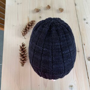 Puede incluir: Un gorro de punto de color gris oscuro con textura acanalada.