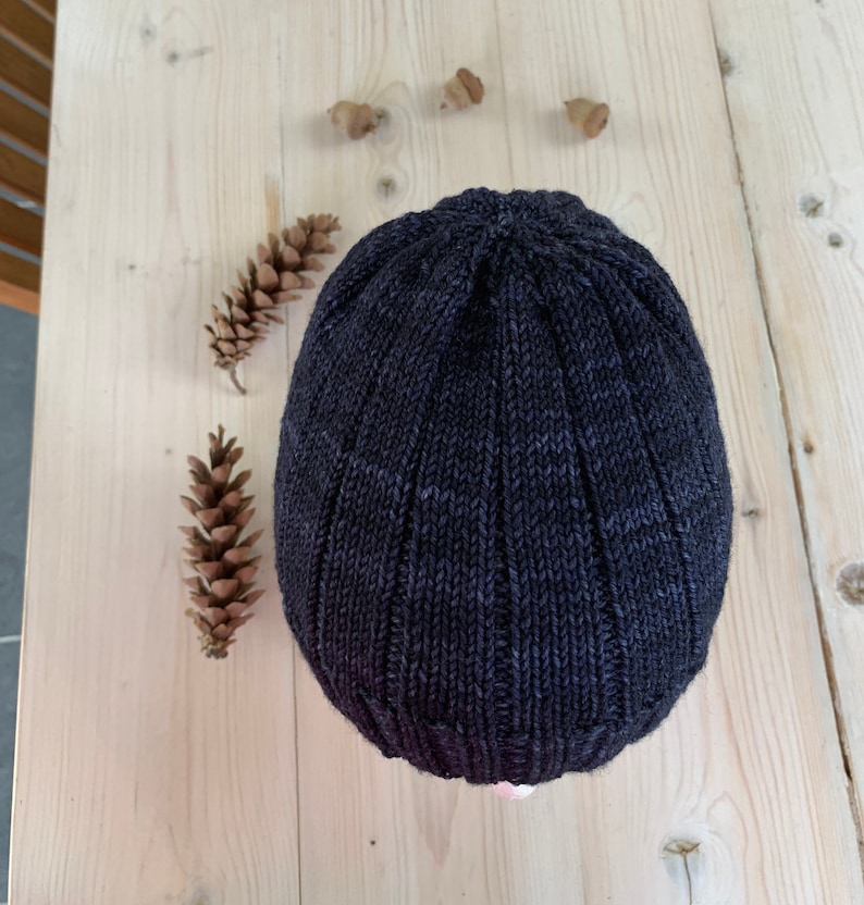 Puede incluir: Un gorro de punto de color gris oscuro con textura acanalada.