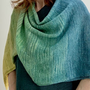 May include: A green, blue, and yellow gradient knitted shawl with a fringed edge.