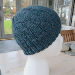 Puede incluir: Un gorro de punto azul turquesa sobre una cabeza de maniqu&iacute; blanca. El gorro tiene una textura acanalada y est&aacute; hecho de un hilo suave.