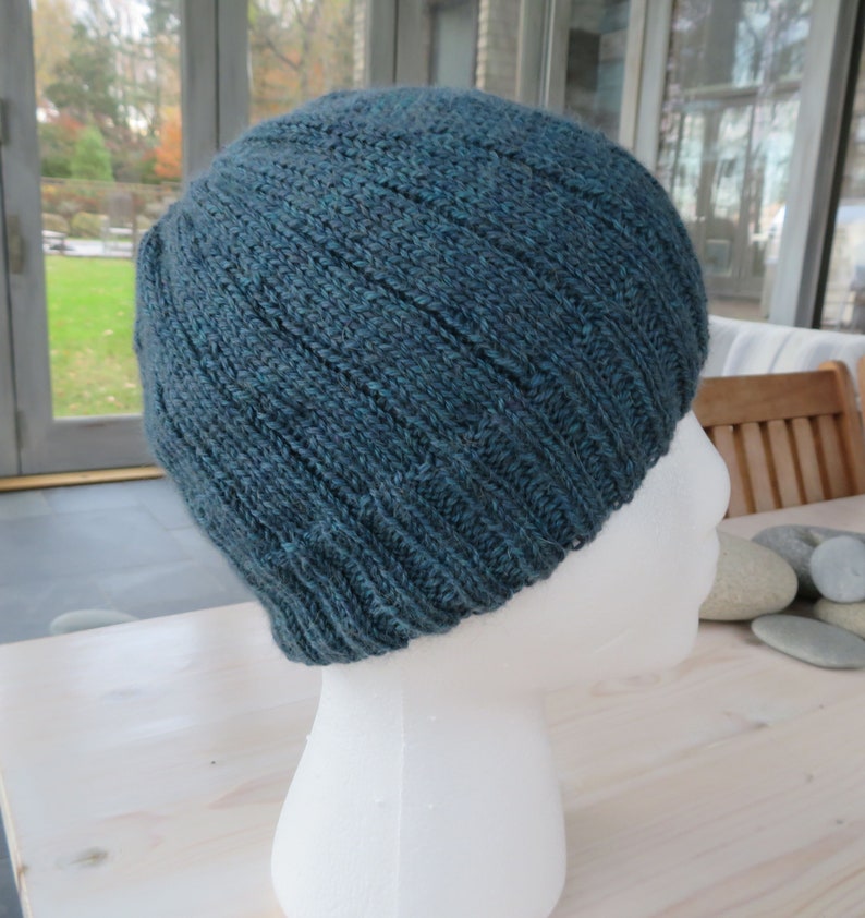Puede incluir: Un gorro de punto azul turquesa sobre una cabeza de maniqu&iacute; blanca. El gorro tiene una textura acanalada y est&aacute; hecho de un hilo suave.