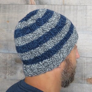Puede incluir: Un gorro de punto de rayas azules y grises. El gorro está hecho de un hilo suave y cálido y tiene un ajuste holgado.