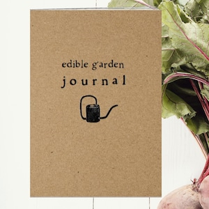 May include: A brown paper journal with the text "edible garden journal" and a small black watering can illustration.