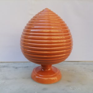 Peut inclure: Un vase en céramique de couleur orange avec un motif côtelé et une base ronde.