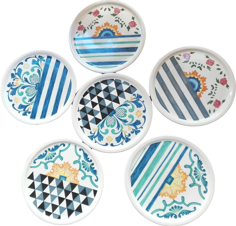 May include: Six ceramic plates with different blue, white, and green geometric and floral patterns. The plates are all round and have a white background.
