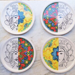 Puede incluir: Cuatro platos de cerámica con un diseño dividido. Cada plato presenta un contorno en blanco y negro de una cara en una mitad y un patrón floral colorido en la otra mitad.