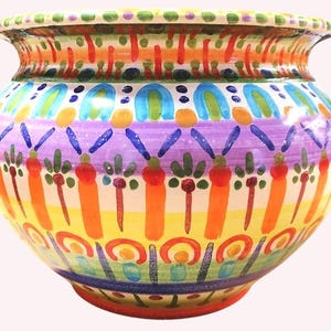 Può includere: Un vaso in ceramica dipinto a mano con un corpo ampio e arrotondato e un bordo leggermente svasato. Il vaso presenta un design vibrante con strisce verticali arancioni, alternate a fasce viola, gialle e blu. Il bordo è decorato con punti verdi e rossi.