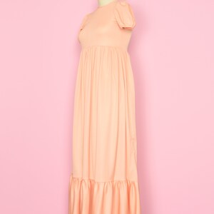 May include: A peach-colored maxi dress with a round neckline, short puff sleeves, and a tiered skirt.