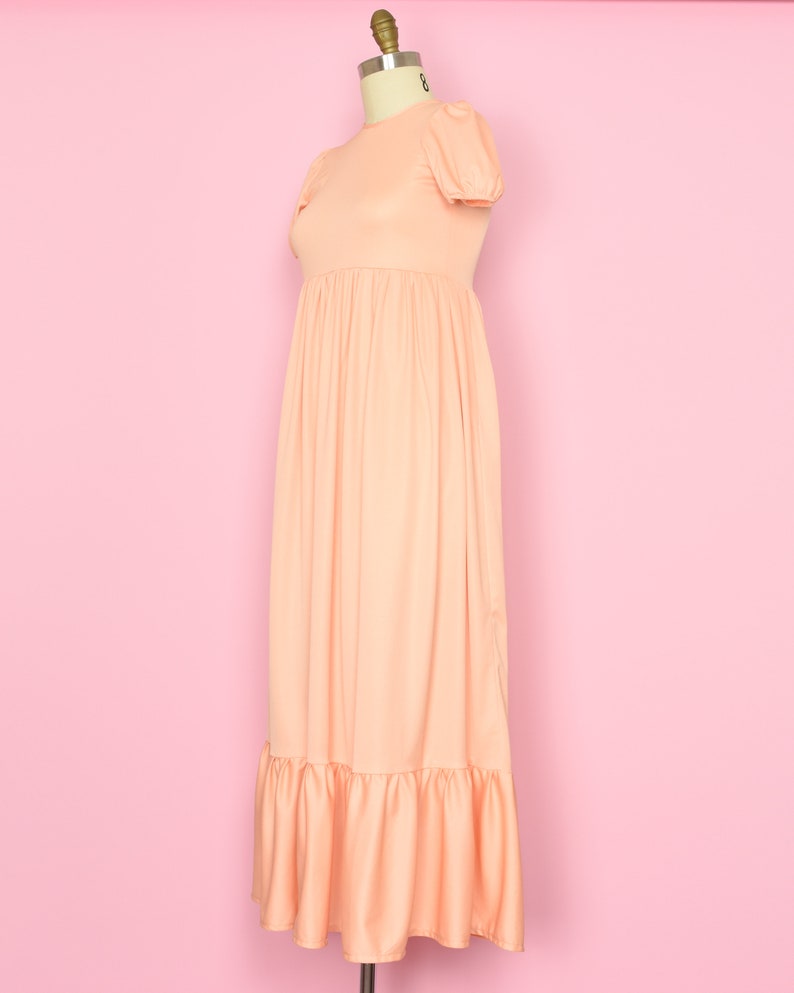 May include: A peach-colored maxi dress with a round neckline, short puff sleeves, and a tiered skirt.