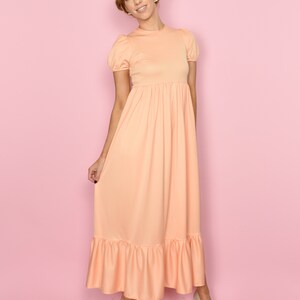 May include: A peach-colored maxi dress with a ruffled hem and short puff sleeves. The dress has a fitted bodice and a flowy skirt.