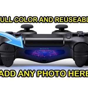 May include: A black PlayStation 4 controller with a customizable faceplate featuring a Spiderman design. The faceplate is translucent and glows blue when the controller is turned on. The text "FULL COLOR AND REUSABLE" is above the controller, and the text "ADD ANY PHOTO HERE" is below the controller.