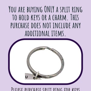 May include: A silver split ring for holding keys or charms. The image includes text that reads: "YOU ARE BUYING ONLY A SPLIT RING TO HOLD KEYS OR A CHARM. THIS PURCHASE DOES NOT INCLUDE ANY ADDITIONAL ITEMS. PLEASE PURCHASE SPLIT RING FOR KEYS AS AN ADD-ON."