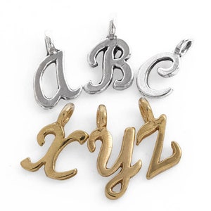 Könnte beinhalten: Silberne und goldene Anhänger mit geschwungenen Buchstaben. Die silbernen Anhänger sind die Buchstaben a, b und c. Die goldenen Anhänger sind die Buchstaben x, y und z.