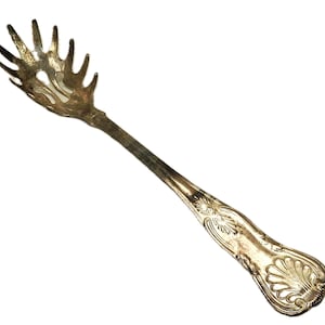 Puede incluir: Un servidor de espaguetis plateado con un mango adornado y un diseño decorativo. El servidor tiene un mango largo y delgado con un extremo ancho y plano diseñado para recoger espaguetis.