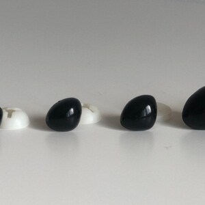May include: Four black plastic safety eyes of different sizes, with white plastic washers behind them.