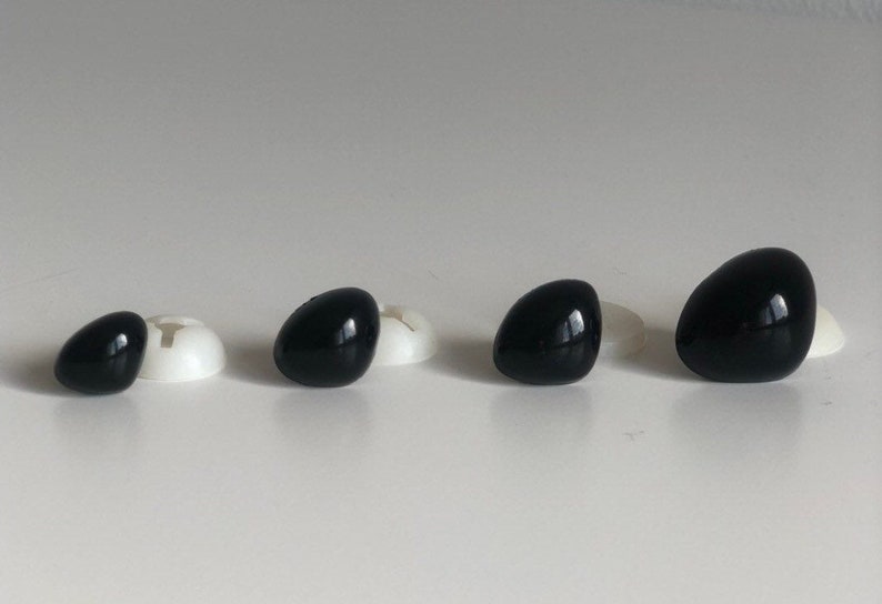May include: Four black plastic safety eyes of different sizes, with white plastic washers behind them.