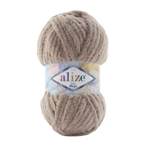 Könnte beinhalten: Ein Knäuel beigefarbenes Garn namens "Baby Alize Softy Mega". Das Garn ist weich und flauschig und perfekt zum Stricken oder Häkeln.