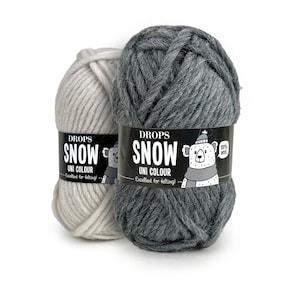 Peut inclure: Deux pelotes de laine Drops Snow, l'une de couleur beige clair et l'autre de couleur gris foncé. La laine est 100% laine et est excellente pour le feutrage. L'étiquette représente un ours polaire en dessin animé portant une écharpe.