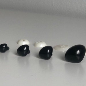 May include: Assortment of black plastic safety eyes for crafts. The eyes come in various sizes and have a flat back with a small screw post.