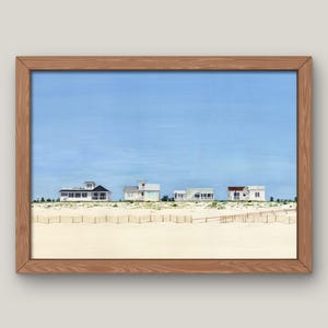 Könnte beinhalten: Ein gerahmter Druck mit einer Strandszene mit vier weißen Häusern entlang der Küste. Die Häuser haben dunkle Dächer und sind vor einem hellblauen Himmel zu sehen. Ein Sandstrand und ein Holzzaun befinden sich im Vordergrund.