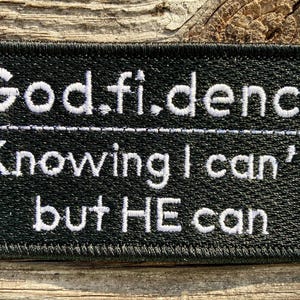 May include: Black fabric patch with white embroidered text that reads "God.fi.dence Knowing I can't but HE can".