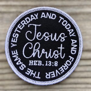 May include: A circular black embroidered patch with a white stitched border. The center features the white text Jesus Christ and HEB. 13:8. The outer edge contains the white text THE SAME YESTERDAY AND TODAY AND FOREVER in a circular pattern.