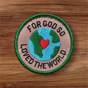 May include: Embroidered patch with the text "FOR GOD SO LOVED THE WORLD". The patch features a blue and green globe with a red heart in the center, surrounded by a tan border and a green stitched edge.