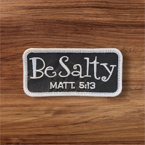 May include: A black and white embroidered patch with the text "Be Salty" and "MATT. 5:13" in white thread. The patch has a white stitched border.