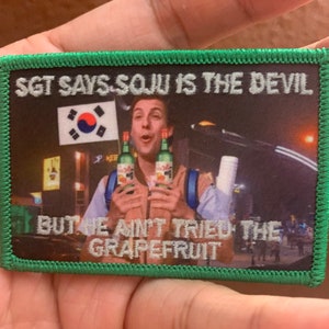 May include: A green embroidered patch with the text "Sgt Says Soju is the Devil but we ain't tried the Grapefruit" and a photo of a man holding two bottles of soju in front of a Korean flag.