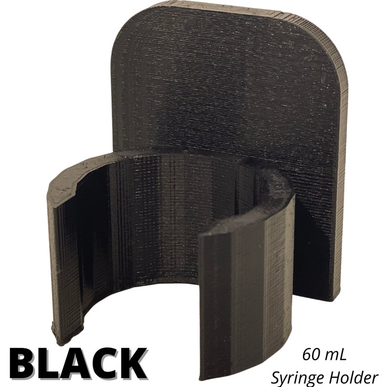 May include: A black 3D-printed syringe holder with a vertical back plate and a semi-circular front clip designed to secure a 60 mL syringe. The object features a textured surface finish and includes the text BLACK and 60 mL Syringe Holder.