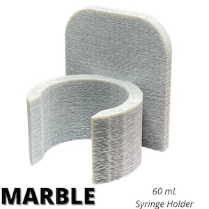 May include: A marble-colored 60 mL syringe holder featuring a C-shaped clip attached to a flat, rounded rectangular backplate. The object has a textured, layered surface finish consistent with 3D printing, with the text MARBLE and 60 mL Syringe Holder.