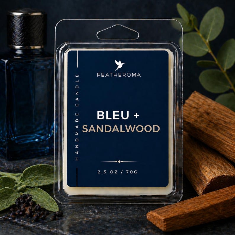 May include: A candle wax melt in a clear plastic clamshell package. The label is navy blue with the text "BLEU + SANDALWOOD" and "FEATHEROMA". The package contains 2.5 oz / 70g of wax. The background includes a blue bottle and wood pieces.