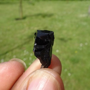 Puede incluir: Una roca de obsidiana negra con una forma irregular y rugosa. La roca es opaca y tiene un brillo v&iacute;treo.