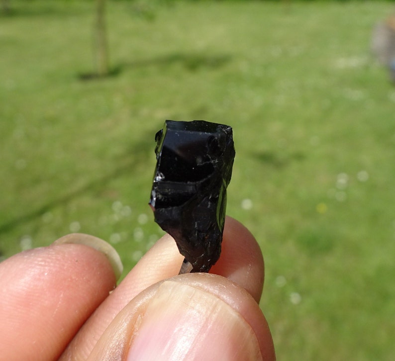 Puede incluir: Una roca de obsidiana negra con una forma irregular y rugosa. La roca es opaca y tiene un brillo v&iacute;treo.