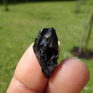 Puede incluir: Una punta de flecha de obsidiana negra con una punta afilada y una superficie rugosa y texturizada.