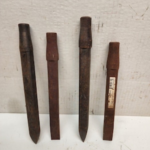 May include: Four rusty metal chisels with wooden handles. The chisels are different sizes and shapes. The chisels are used for carving wood or stone.